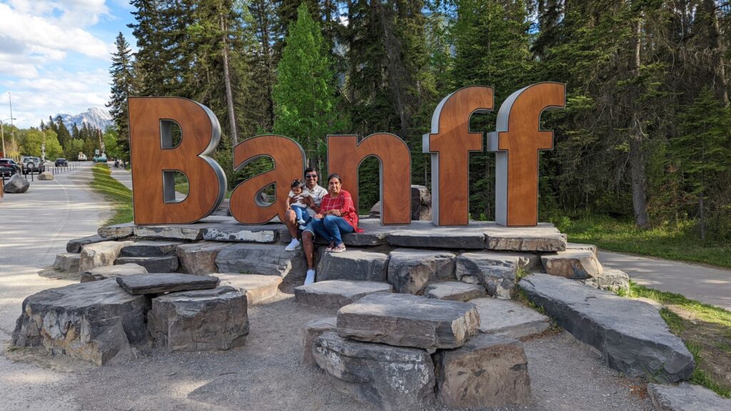 A photo of a family in front of a sign that says Banff.
