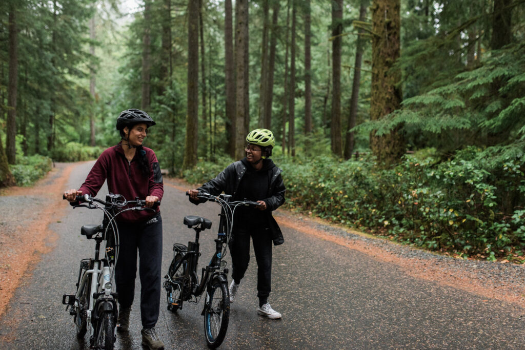 People walking beside bicycles in a forest in BC.