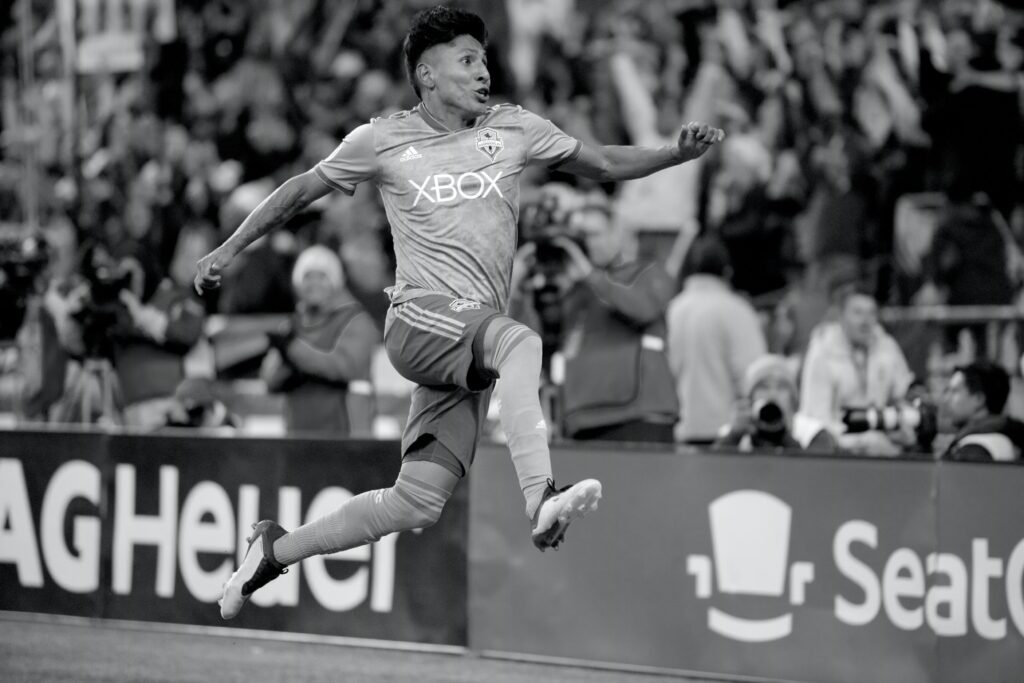 Black and white photo of a soccer player celebrating on the field during an MLS game.