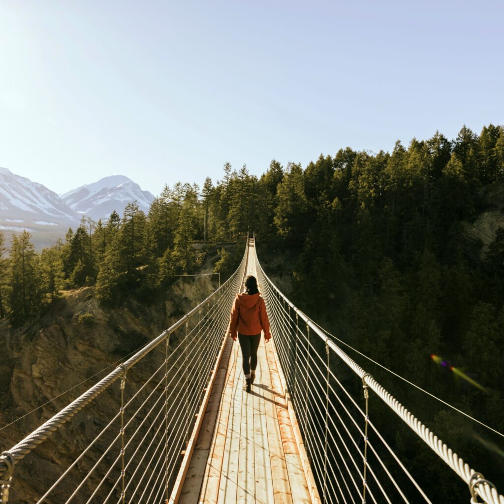 Photo of person walking across bridge in BC using Canoo to travel.