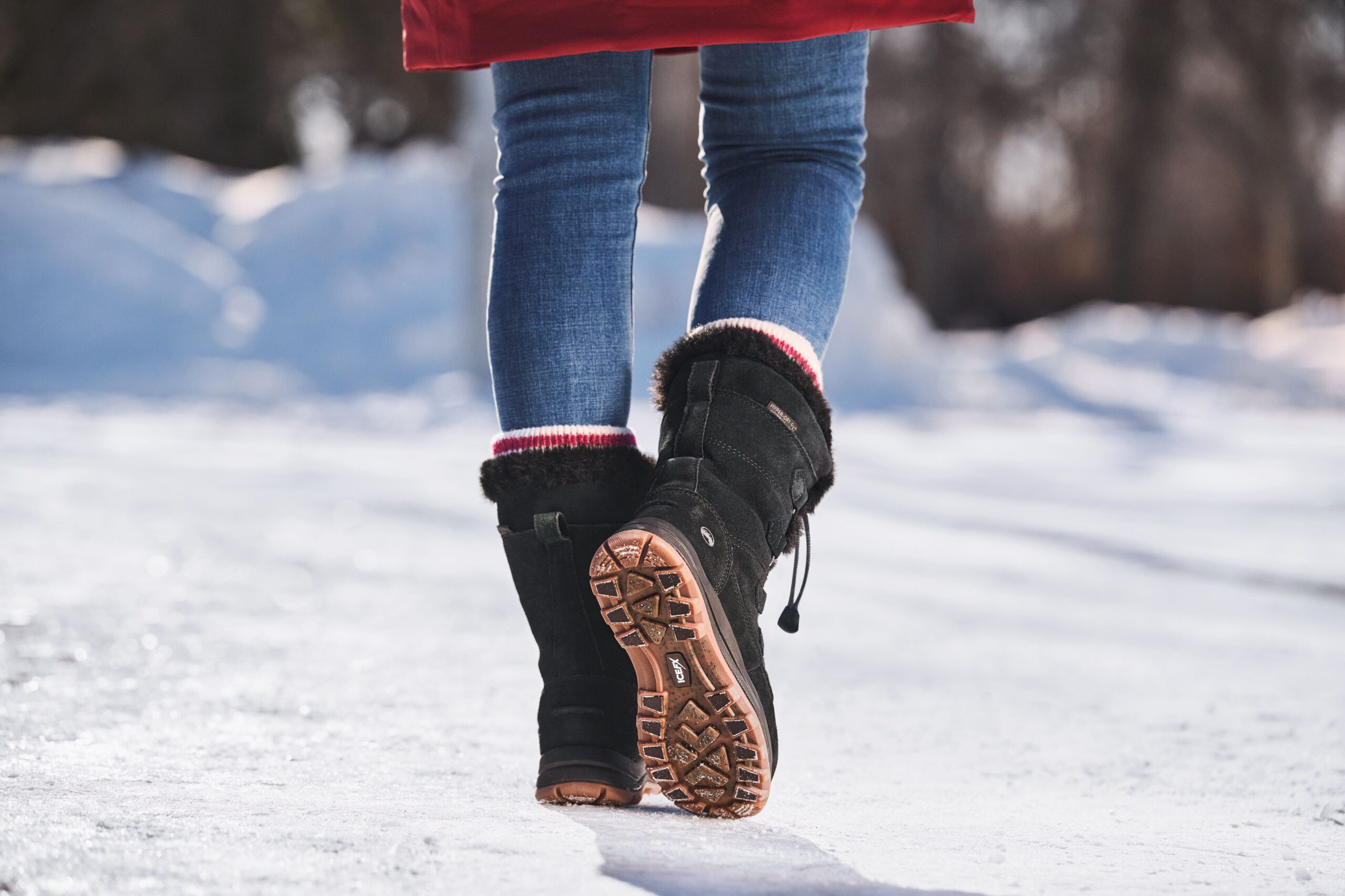 Person walking on snowy ground in winter boots.