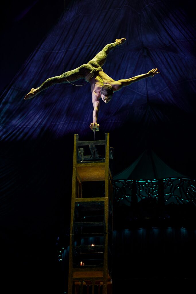 A person balancing on chairs up side down with Cirque du Soleil