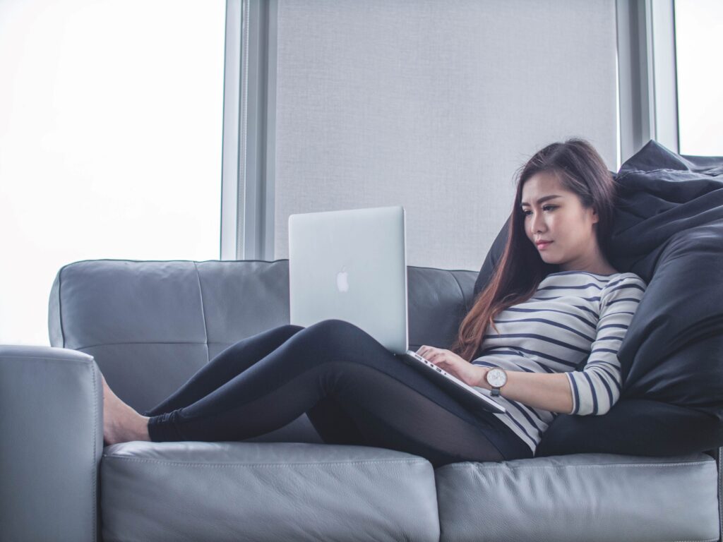 A person filing their taxes on the computer while sitting on a couch.