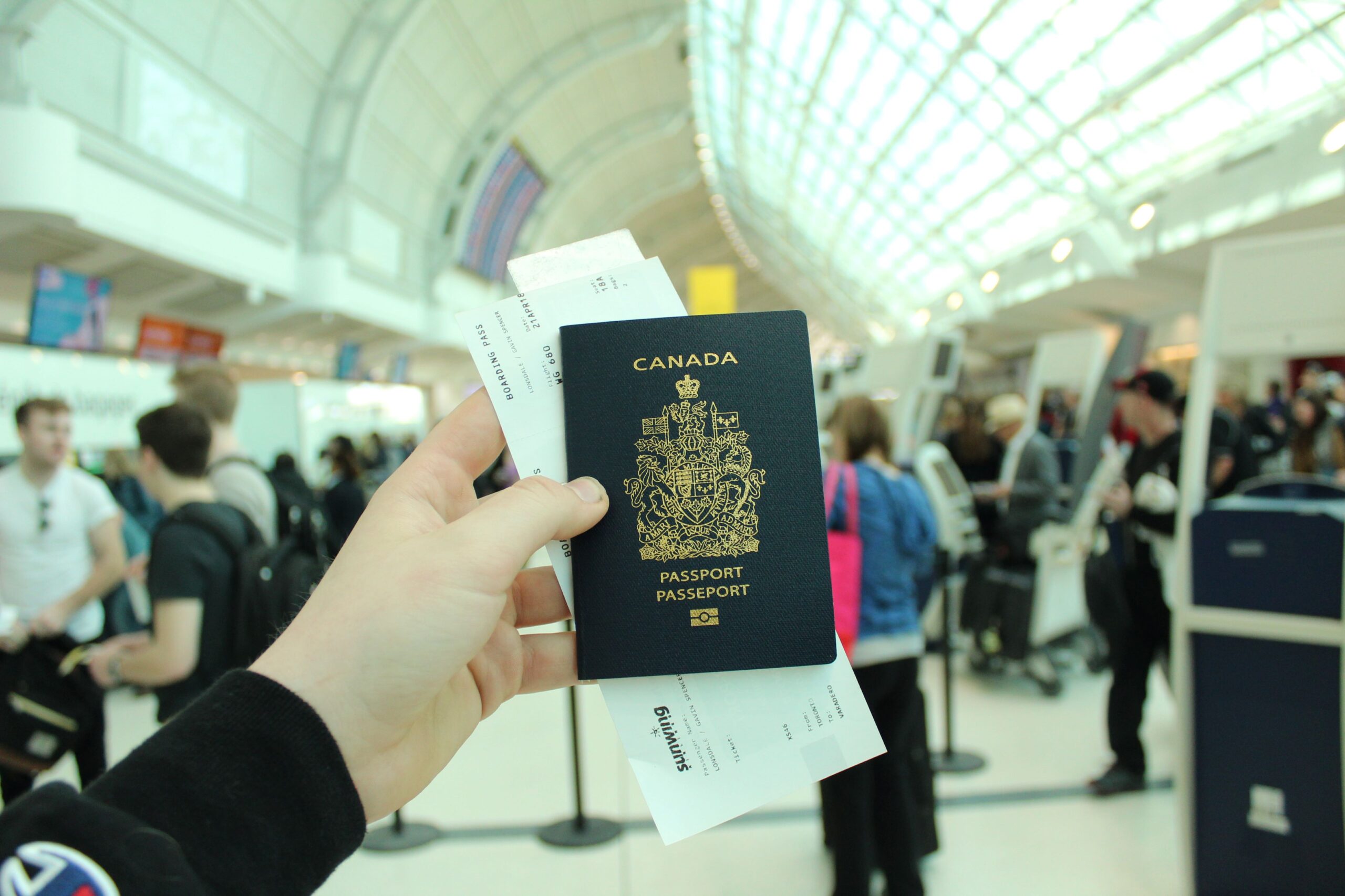 Photo of someone holding up a passport with airplane tickets behind it at an airport.