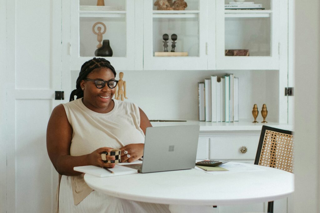 A woman preparing for her financial future while looking at a laptop with a smile on her face.