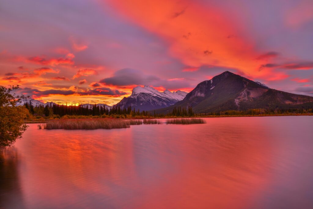 Orange and purple skies, with a sunset over a lake featuring mountains in the background.