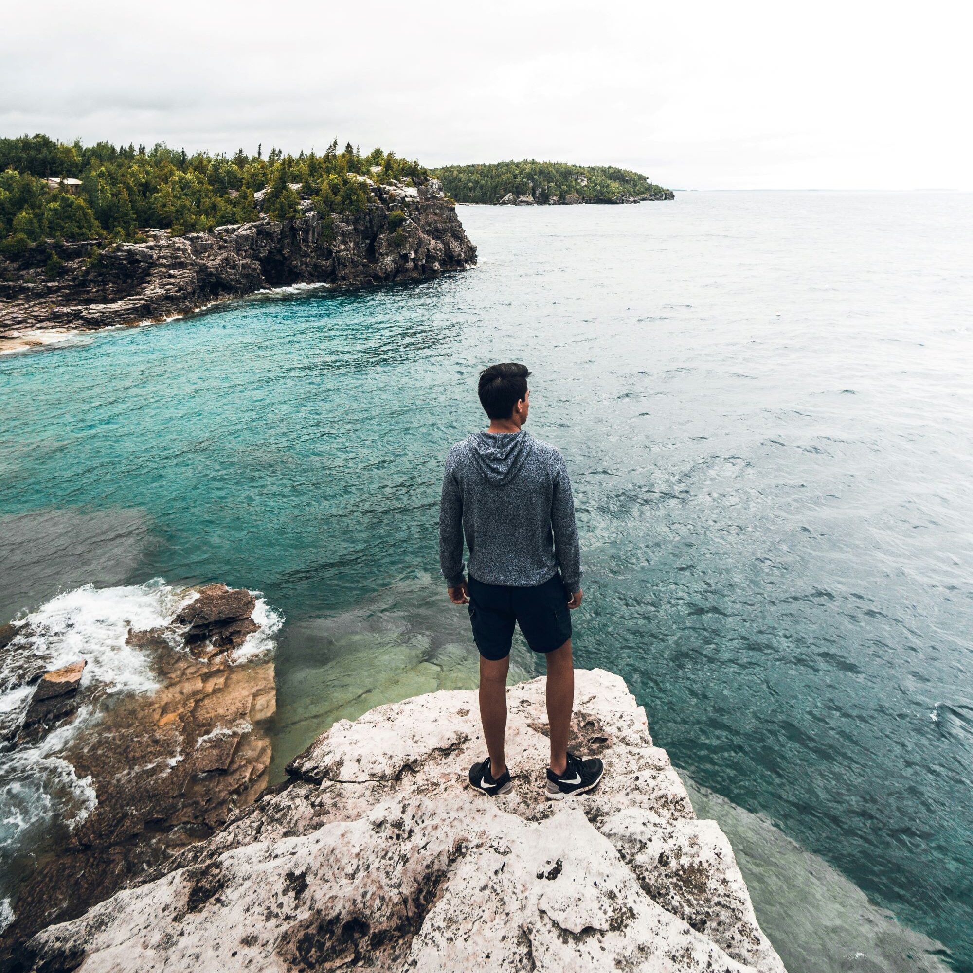 Person standing at Tobermory cliffs - one of the prettiest towns in Ontario.