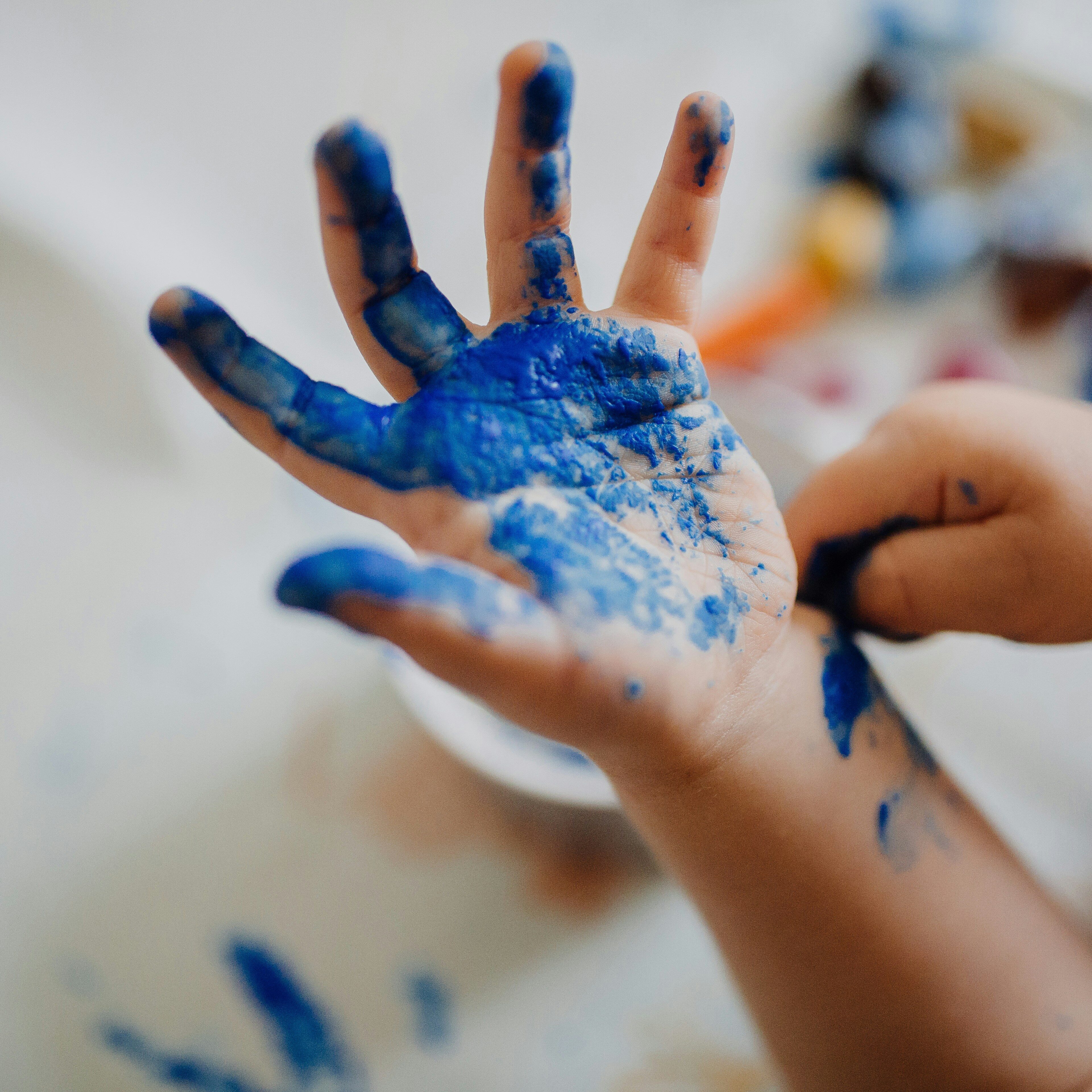 A child’s hand with blue paint on it after making arts and crafts.