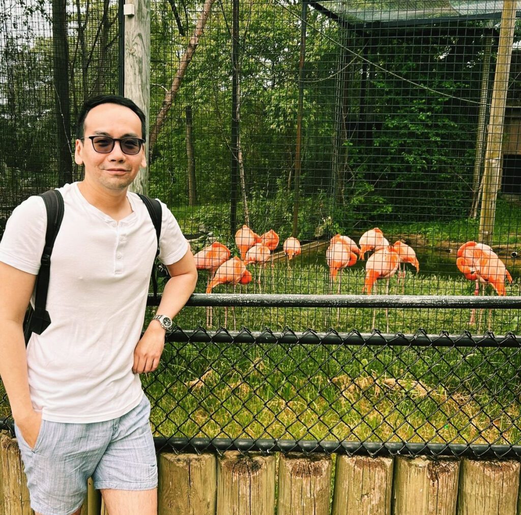 Julian Halim in front of flamingos at the Toronto Zoo.