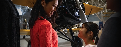 Photo of a mother and child at Ingenium's Canada Aviation and Space Museum in front of a plane.