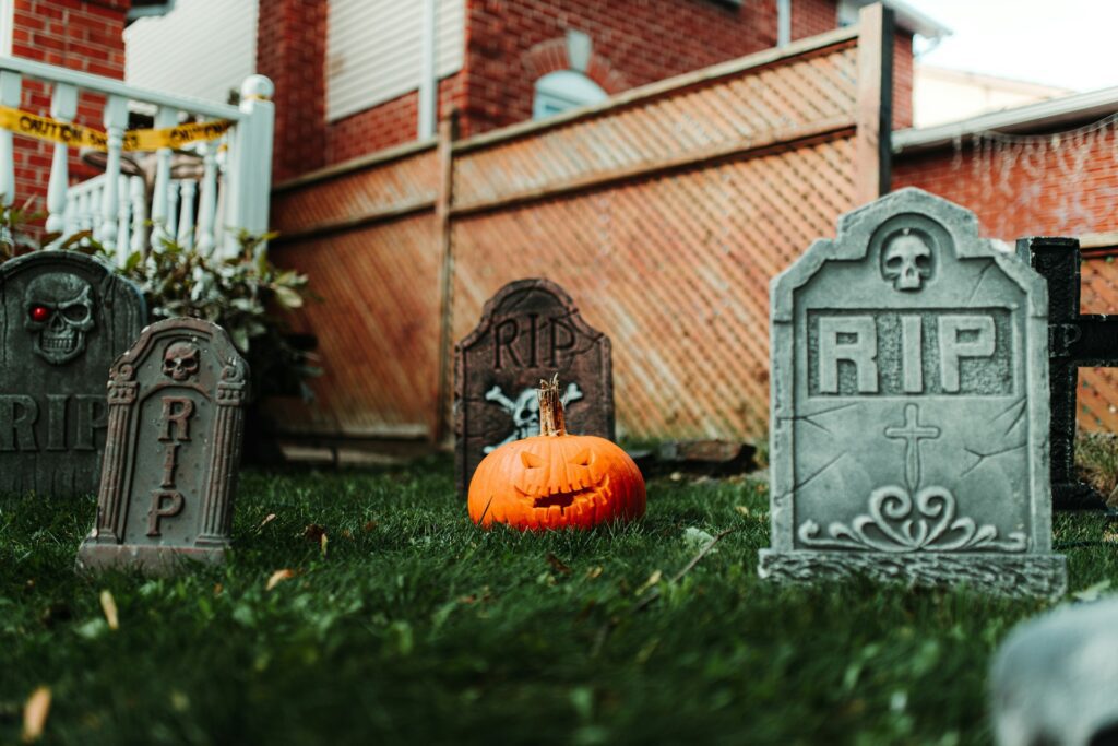 A cemetery with tombstones and a pumpkin in the grass as part of Halloween decorations