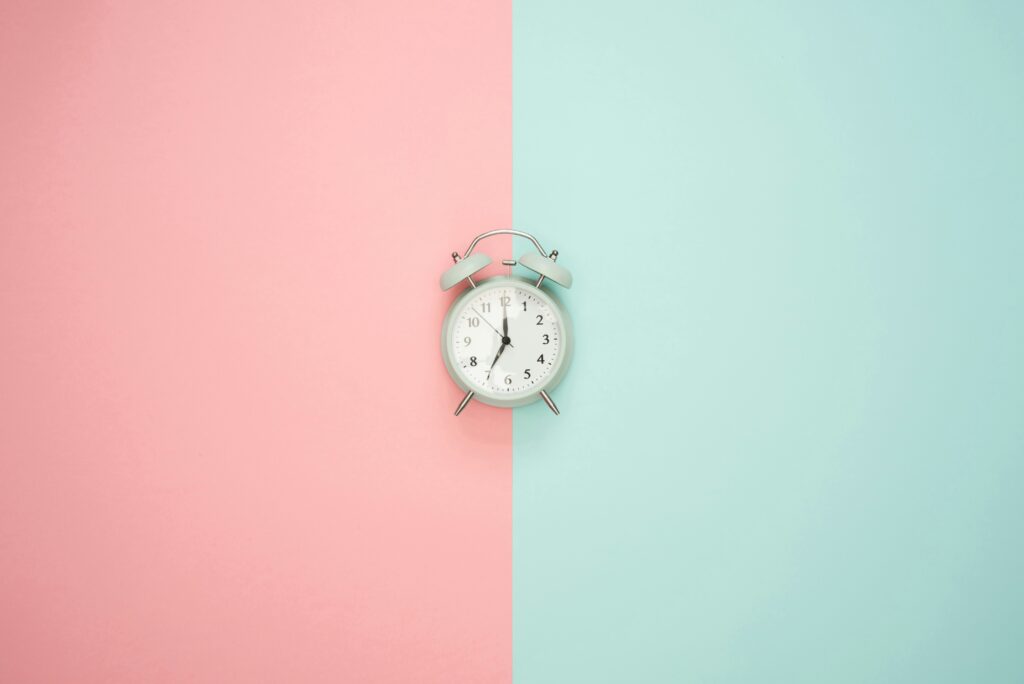 Bell alarm clock on a vertically split blue and pink background