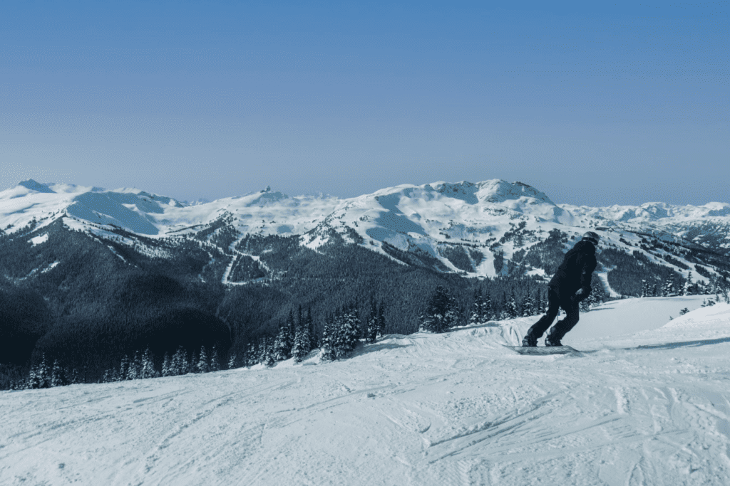 A man riding a snowboard down the side of a snow-covered slope 