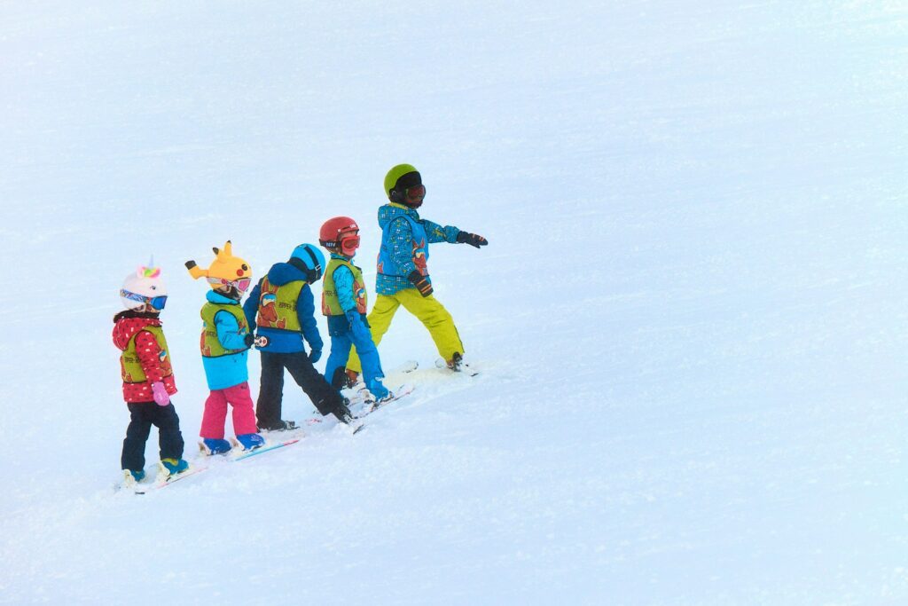 Group of young children with skis on a snow-covered slope 