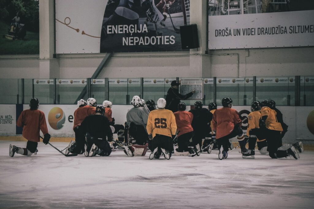 hockey coach in front of hockey players in an ice rink 

 