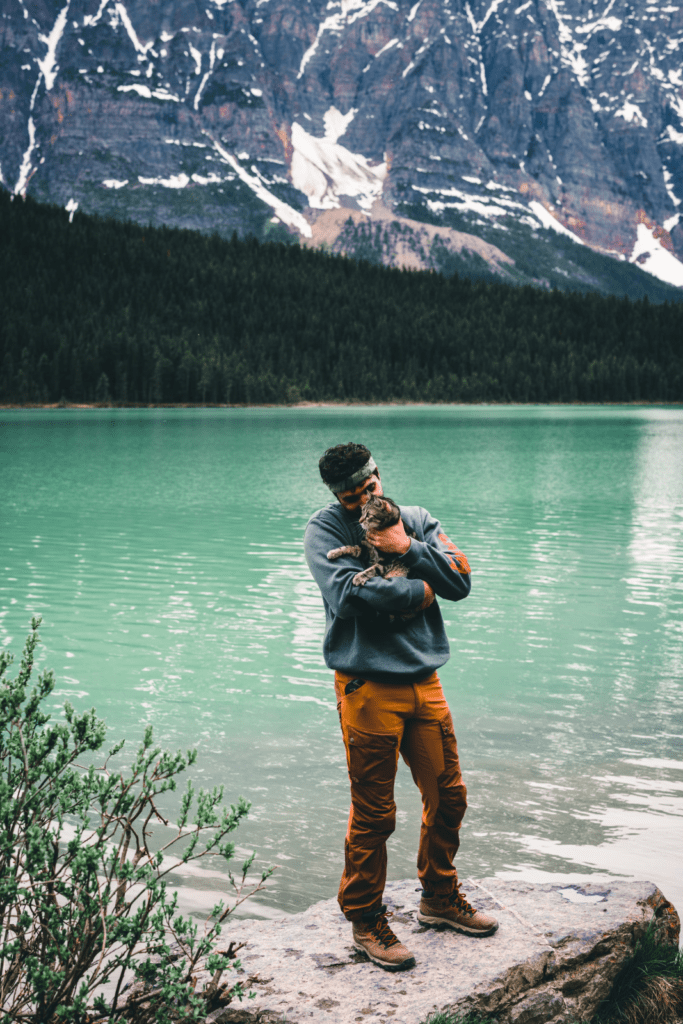 A man standing on a rock next to a lake 