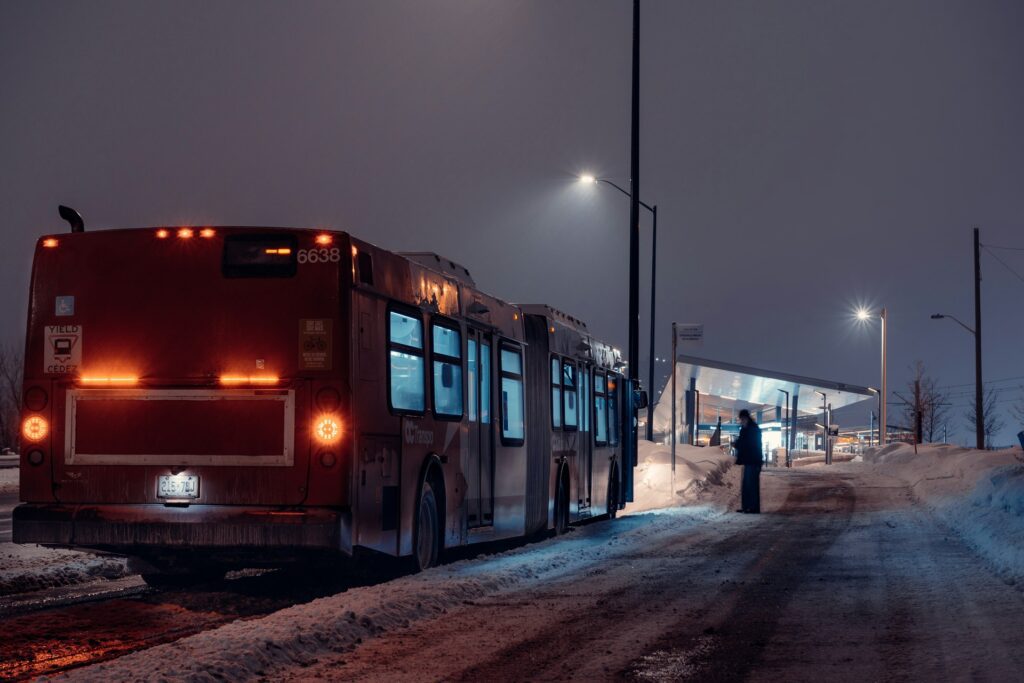 red bus on snow covered road during nighttime 