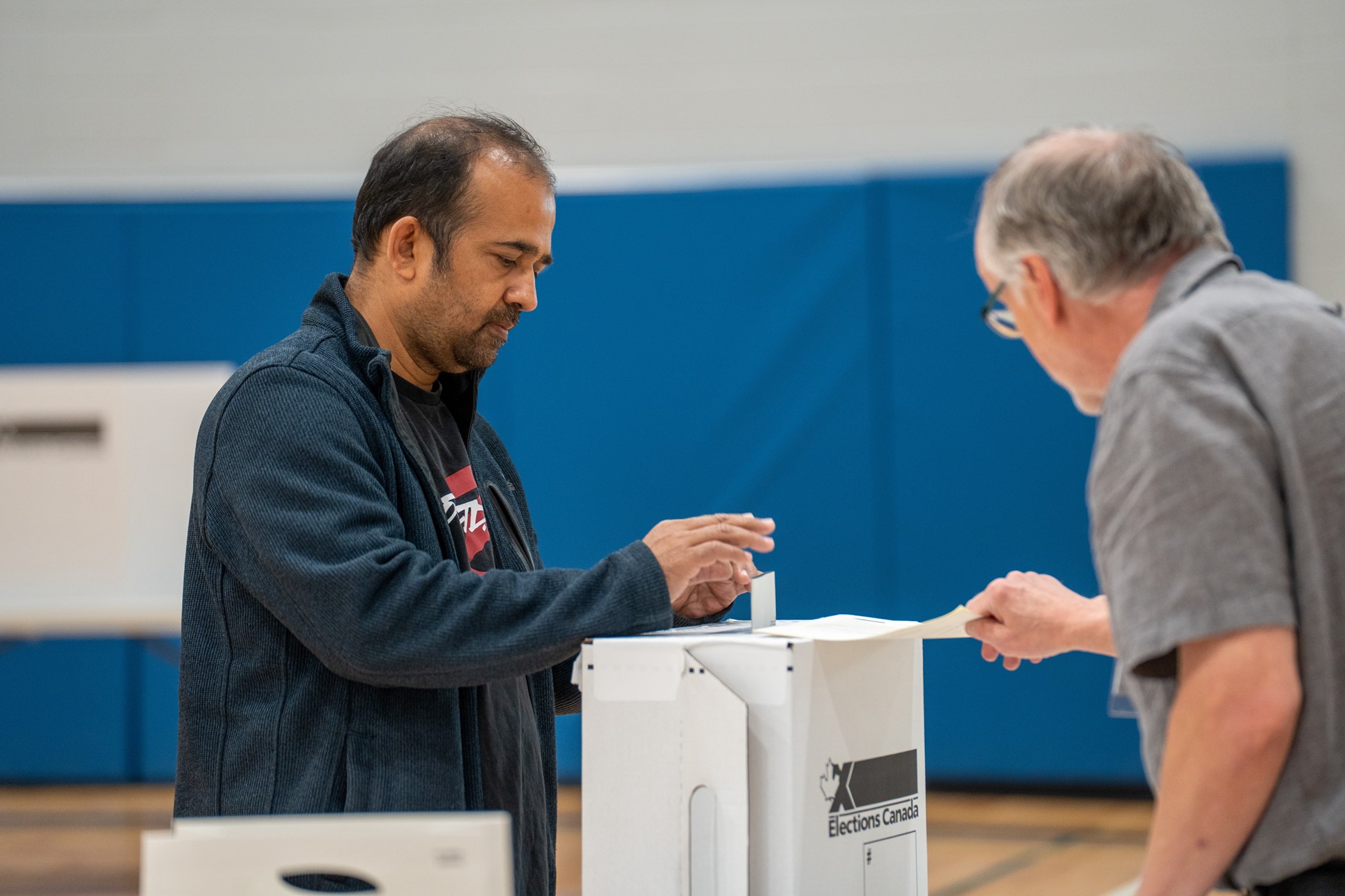 A man placing a ballot in a box in a Canadian federal election.