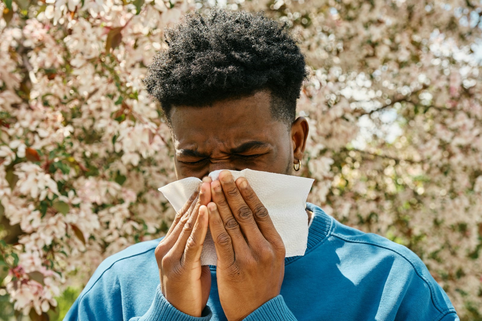 Person sneezing due to seasonal allergies.