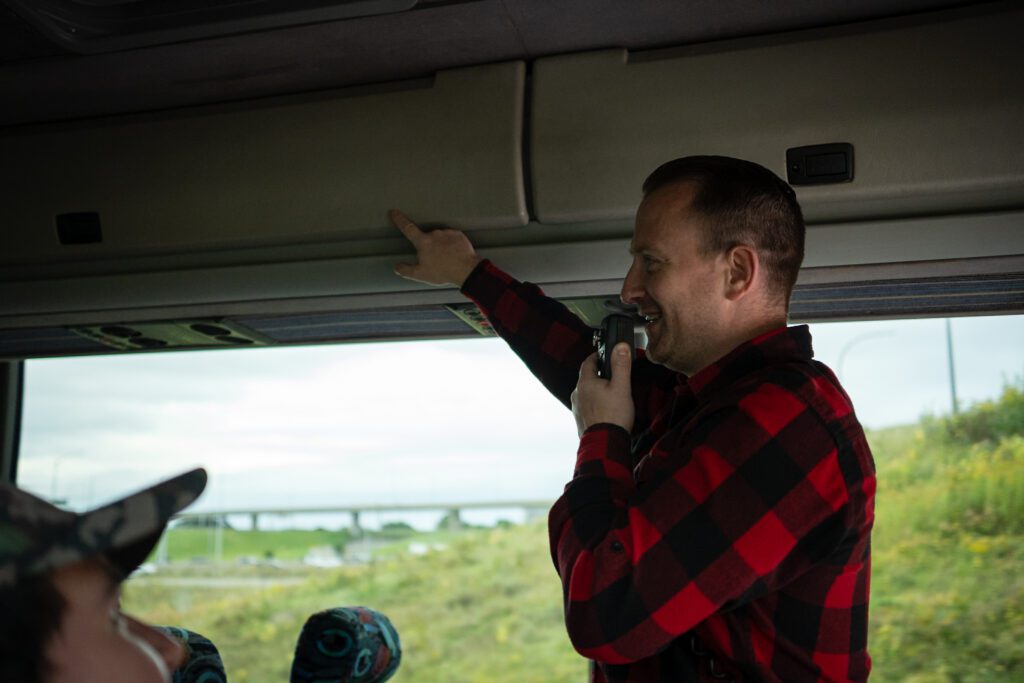 Image of man speaking into a microphone on a tour bus.